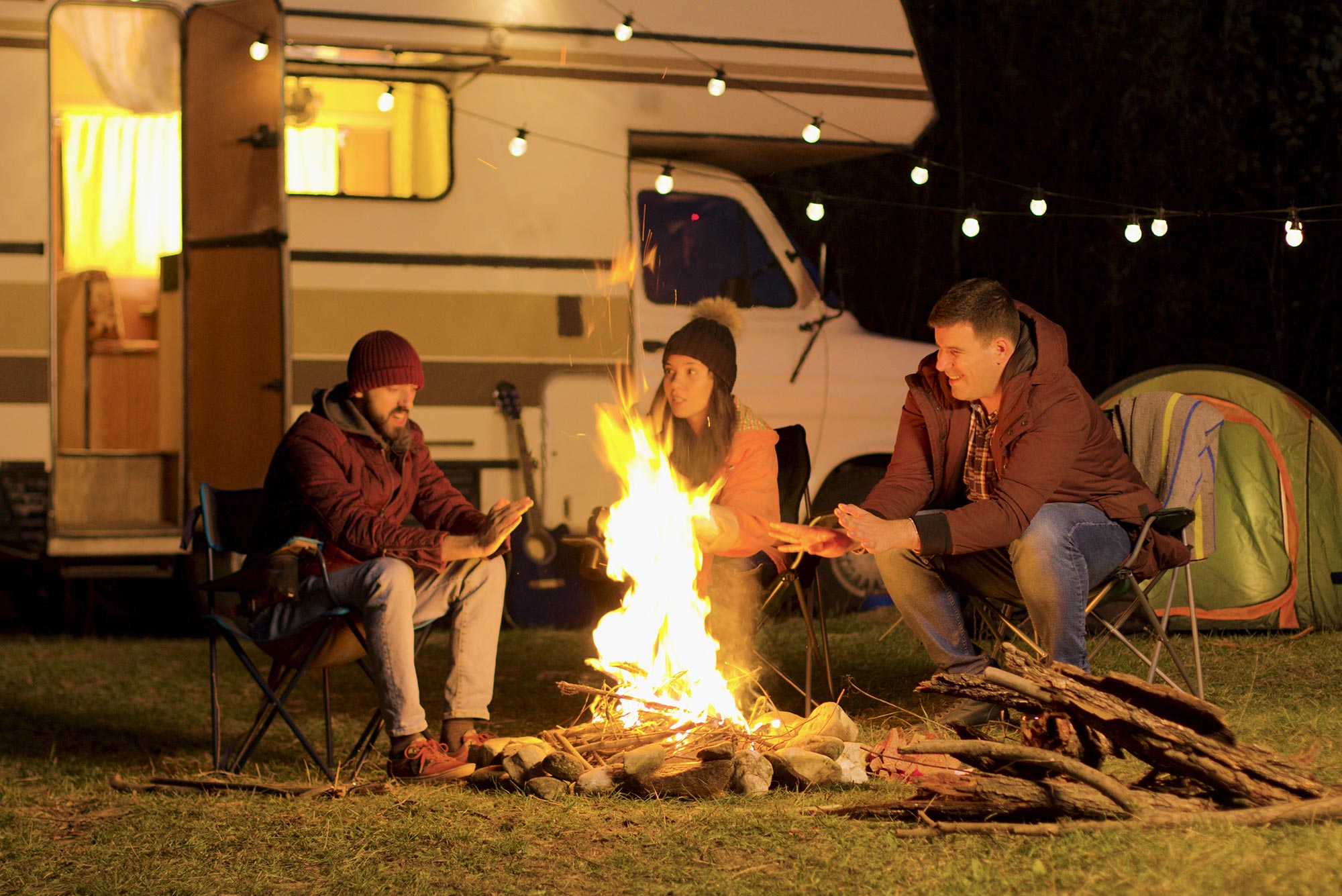 Photo of people sitting around campfire in front of a motorized RV
